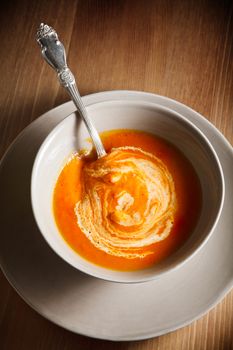 Pumpkin soup with a spoon on a wooden surface