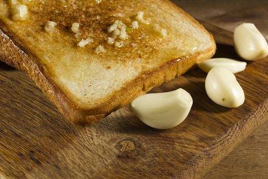 Roasted garlic bread close-up, and cloves of fresh garlic