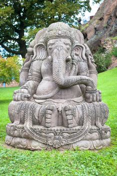 Ganesha statue, made of stone, with a beautiful mountain garden in background