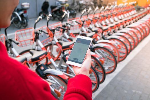 A young woman is looking at smart phone to find her bicycle