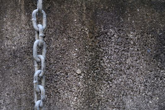 Chain Hanging On A Concrete Wall Background.