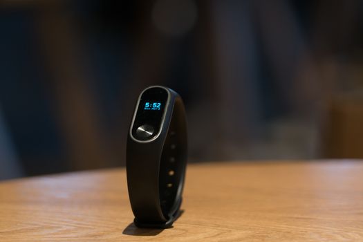 A clock of fitness smart band device on wooden table