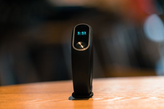 A clock of fitness smart band device on wooden table