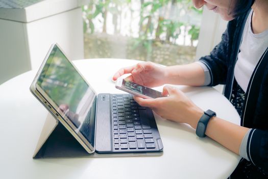 Young student women wearing smart band touching smart phone while using tablet computer