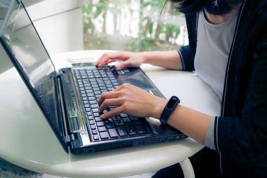 Young student women wearing smart band using laptop computer