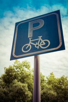 bicycle parking sign on blue sky and tree with filter