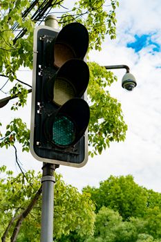 Green light of traffic light on the pole with the tree and blue sky