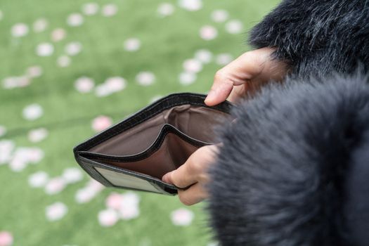 Hand holding empty wallet. The woman show her empty purse on hand. poor girl.