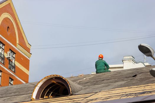 worker in a helmet sit on the building roof