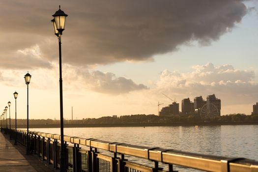 seafront with fence and street lanterns. clouds