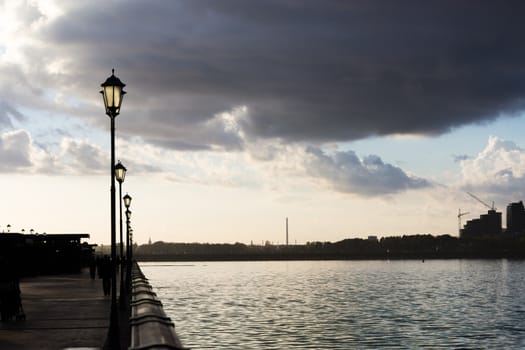 seafront with fence and street lanterns. clouds