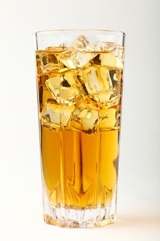 One full high glass of cold iced black tea with transparent ice rocks cubes over white, close up, low angle view