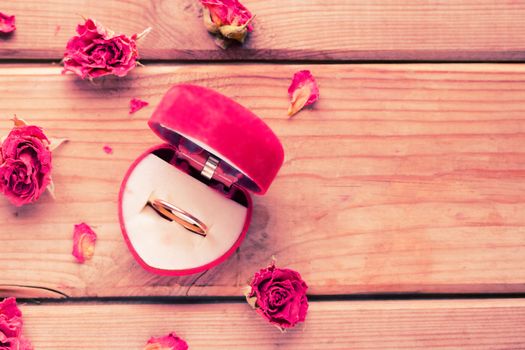 Golden engagement ring in a heart shaped box and roses