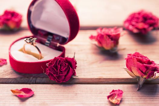 Golden engagement ring in a heart shaped box and roses