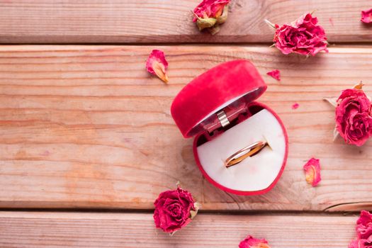Golden engagement ring in a heart shaped box and roses