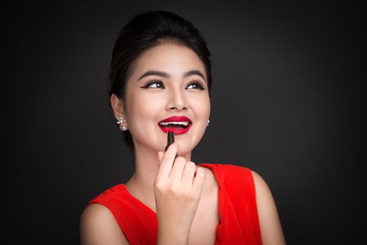 Professional Make-up. Attractive asian model applying red lipstick. 