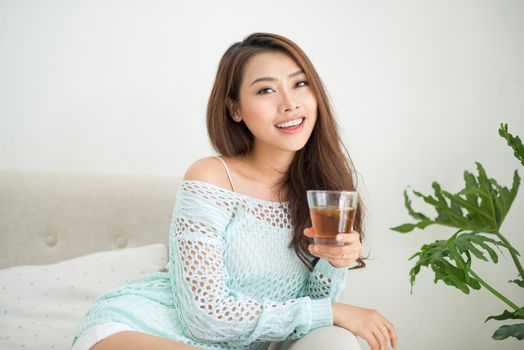 Beautiful young asian woman drinking her morning tea over a breakfast at home.