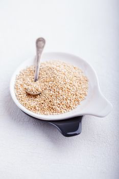 Raw quinoa in a white plate on wooden table