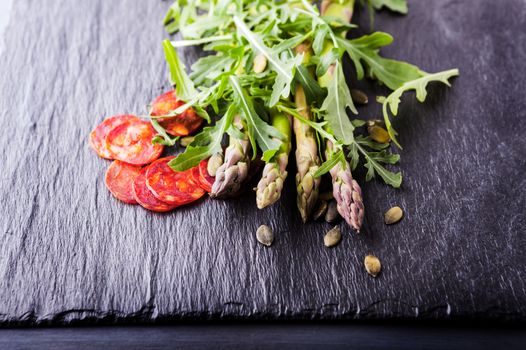 Fresh vegetables with slices of chorizo on a stone plate