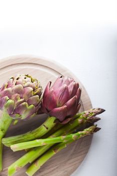 Artichokes and asparagus on a wooden board