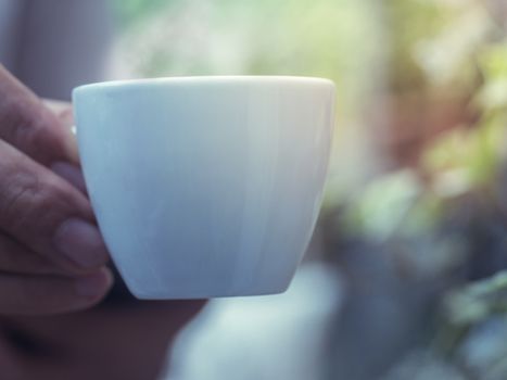 Closeup male hand holding a small coffee cup 