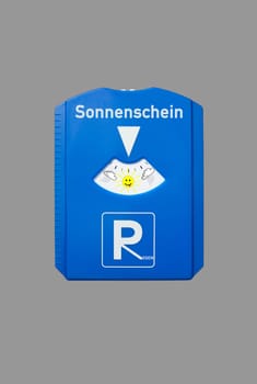 A german parking disc with the german words for sunshine and rain isolated on grey