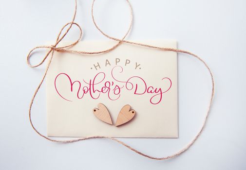 Holidays card with wooden heart and text Happy mothers day. Calligraphy lettering hand draw.