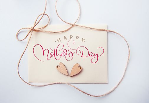 Holidays card with wooden heart and text Happy mothers day. Calligraphy lettering hand draw.