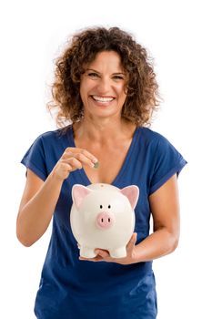 Portrait of a happy middle aged woman puting some money on a Piggybank