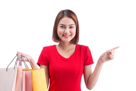 Shopping woman smiling joyful and happy holding shopping bags pointing. Asian female shopper isolated on white.