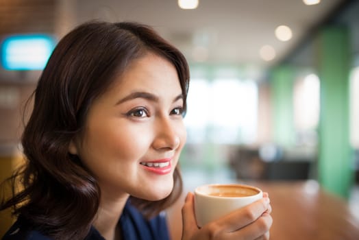 Portrait of attractive young asian woman drinking coffee