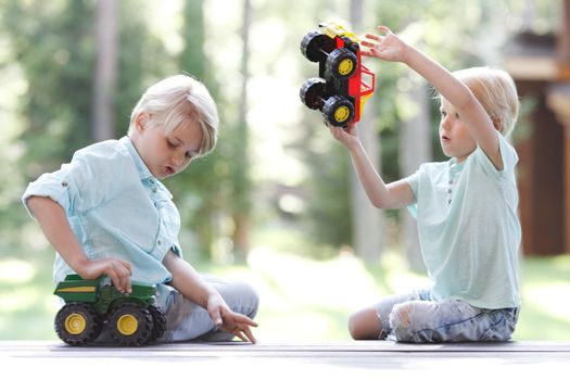 Little brothers playing with toy cars outdoors