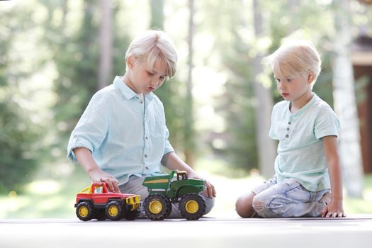 Little brothers playing with toy cars outdoors