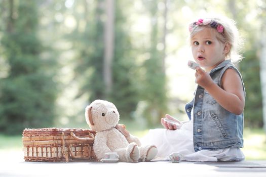 Pretty girl playing with teddy bear outdoors