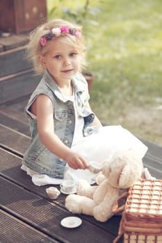 Pretty girl playing with teddy bear outdoors