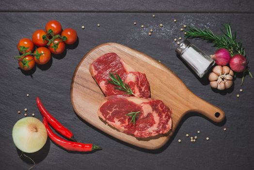 Raw beef on a cutting board  with spices and ingredients for cooking.