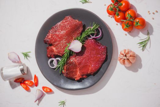 Raw beef on a cutting board  with spices and ingredients for cooking.