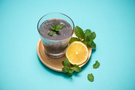 Selective focus of chia seeds drink with water in transparent glass with lemon balm. 