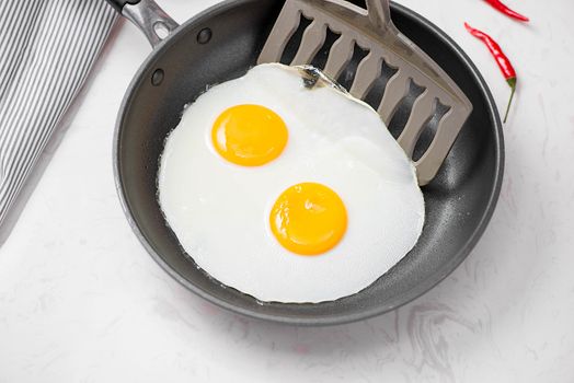 Top view of traditional healthy easy quick breakfast meal made of fried eggs served on a frying pan.