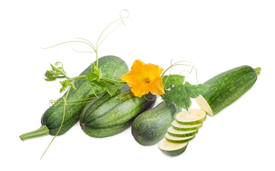 One partly sliced and three whole fresh zucchini and stalk with leaves, tendrils and flower on a light background

