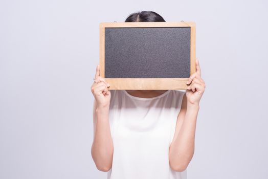 cheerful young woman in white singlet holding sign over gray background