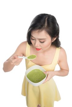 Portrait of asian woman eating/holding a plate of green vegetables soup