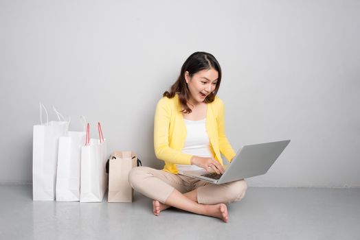 Young asian woman shopping online at home sitting besides row of shopping bags