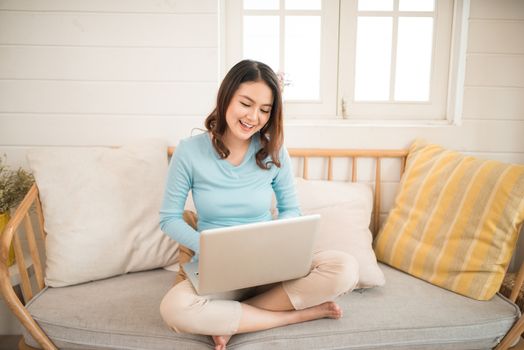 Happy casual beautiful asian young woman working on a laptop at home.