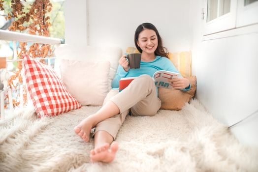 Portrait of young asian woman reading book at home