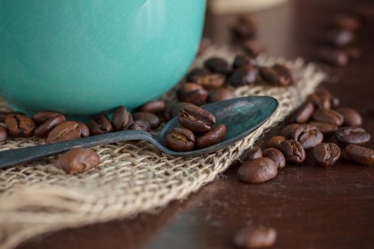 Coffee beans with spoon on wooden floor.