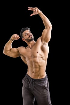 Handsome bodybuilder doing classic double biceps pose, looking away, isolated on black background