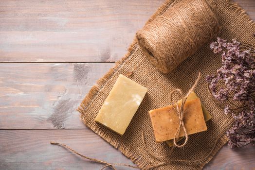 Natural soap with dried flowers on wooden background.