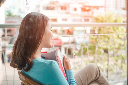 Asian smiling woman reading novel book at home.