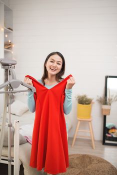 A lovely asian girl trying on new dress at home.